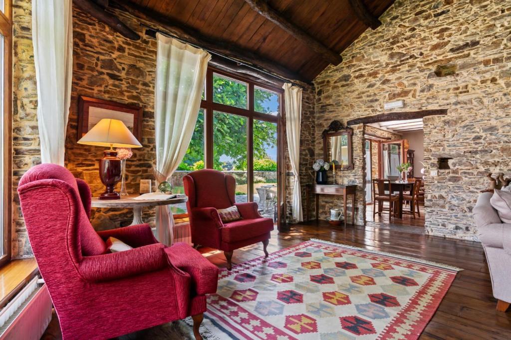 a living room with two chairs and a stone wall at Casa Peleyón in Castropol