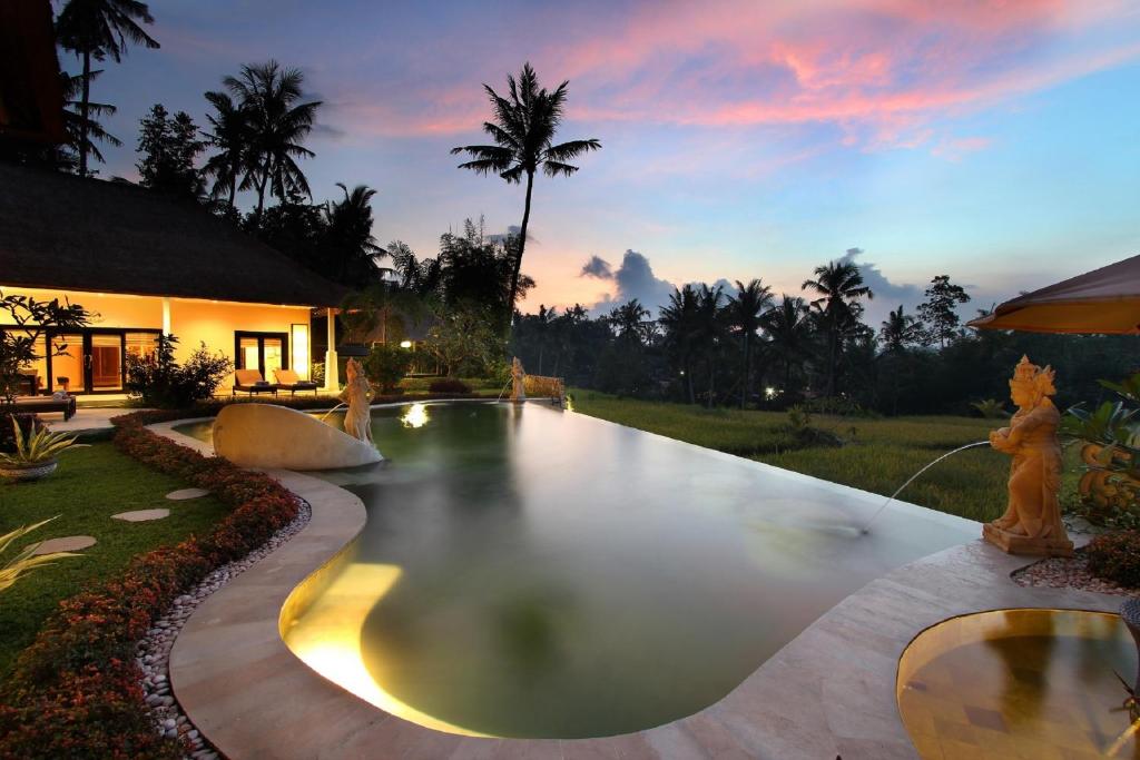 uma piscina no meio de uma casa em Frangipani Villas em Ubud