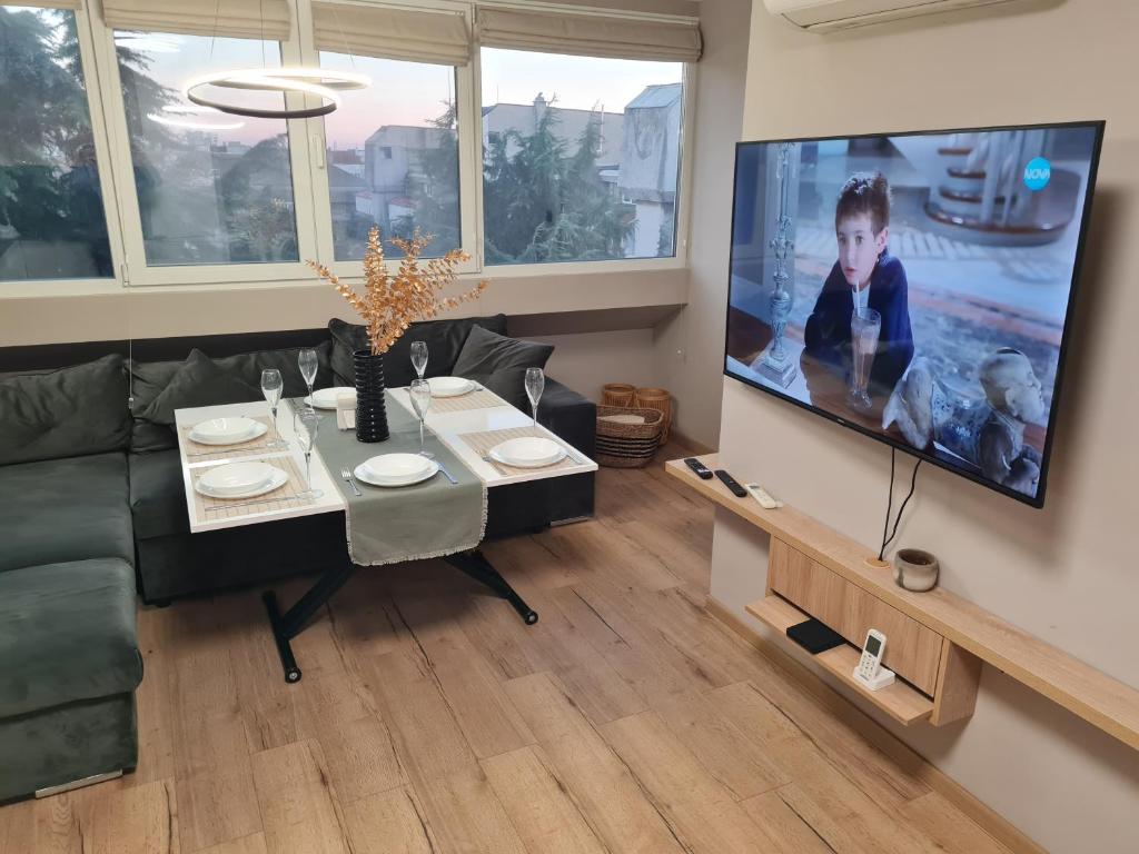 a living room with a table and a tv at Чудесен нов апартамент Илинден in Varna City