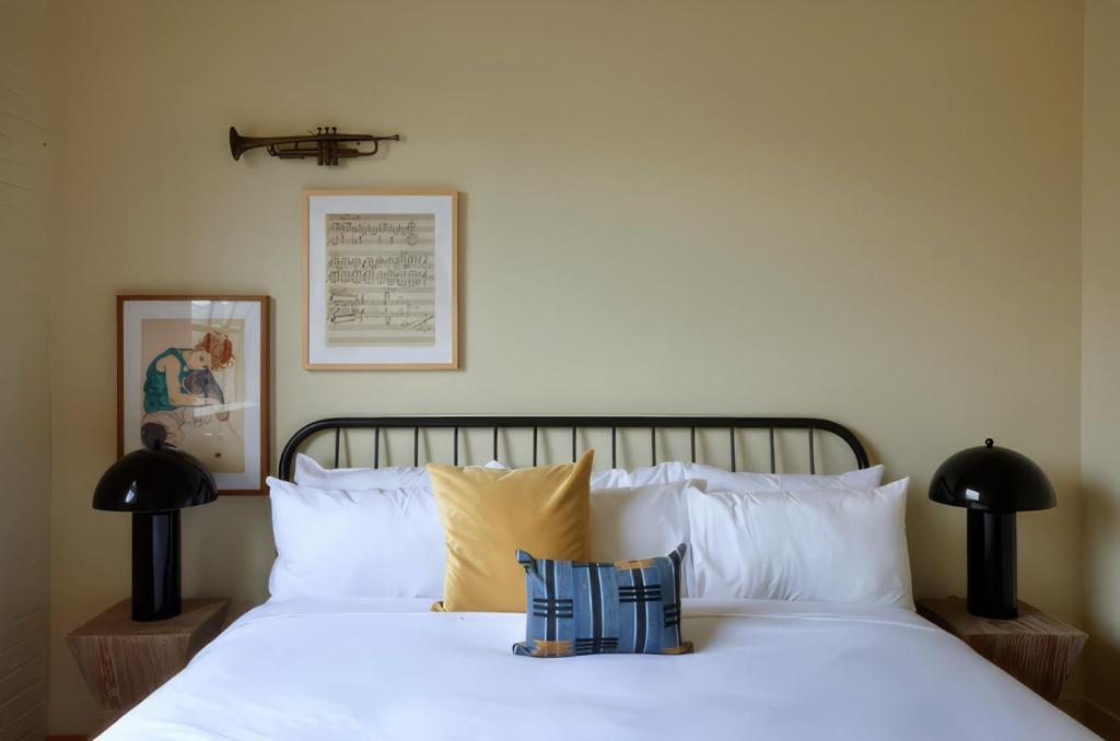 um quarto com uma cama com lençóis brancos e almofadas em Constance Lofts by Black Swan em Nova Orleans