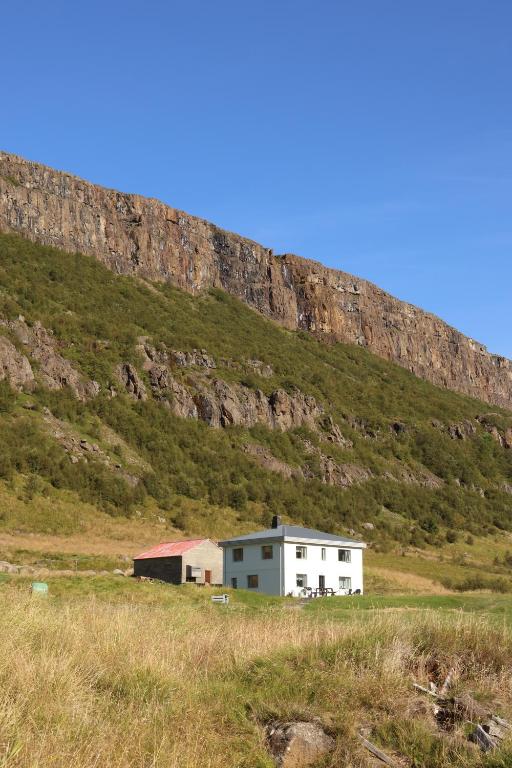een huis in een veld naast een berg bij Hóll in Óbyggðasetur