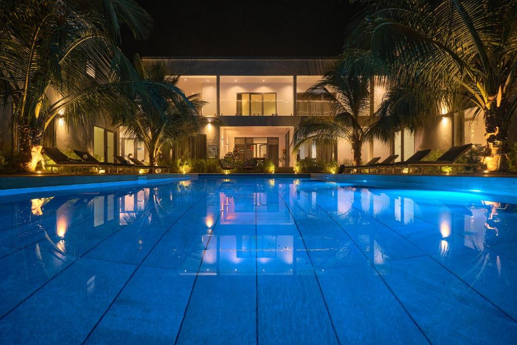 a large swimming pool with palm trees in front of a building at Résidence Gabriel in Sali Nianiaral