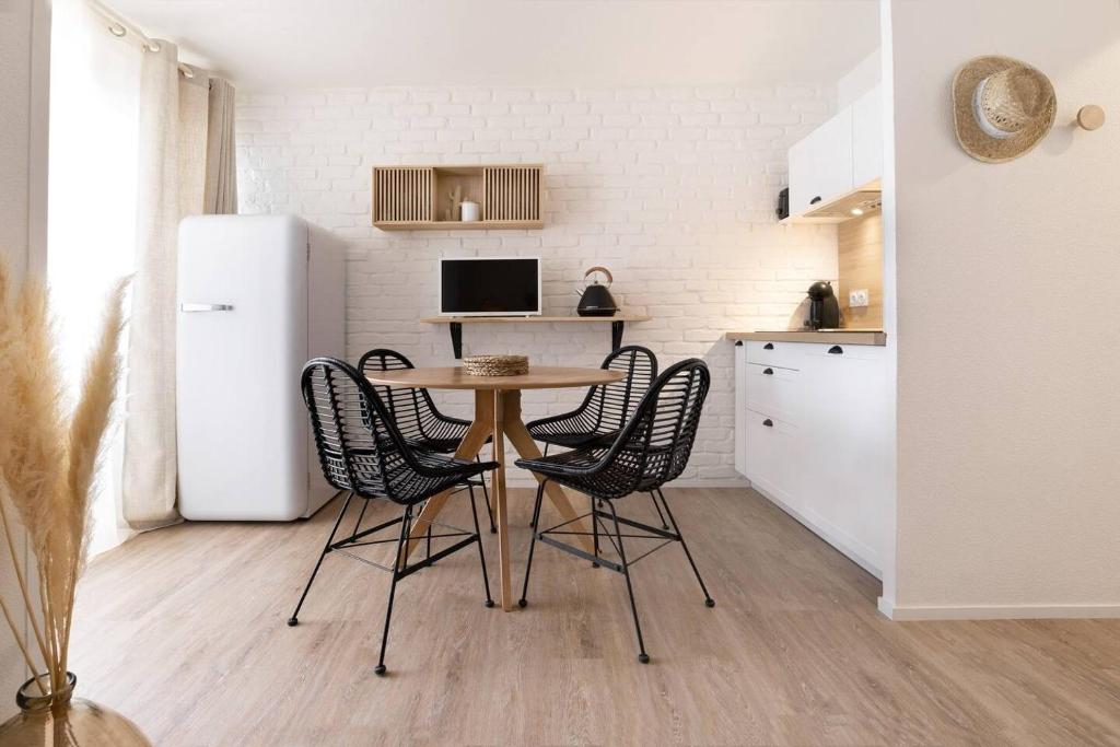 une cuisine avec une table, des chaises et un réfrigérateur dans l'établissement La Petite Mer-Veille avec vue mer et parking privé, à Canet