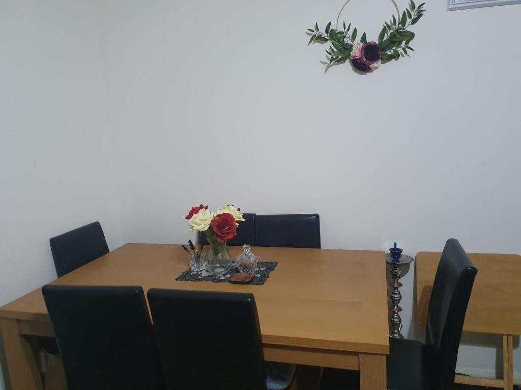 einen Tisch mit Stühlen und eine Vase mit Blumen darauf in der Unterkunft The Hidden Gem in Watford