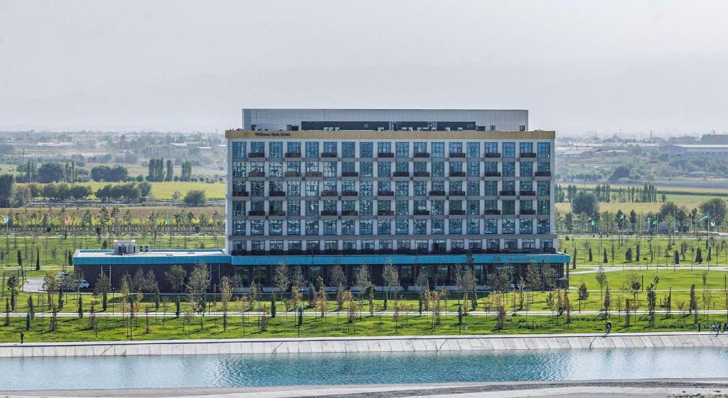 un gran edificio con un lago frente a él en Hilton Garden Inn Samarkand Sogd en Samarcanda