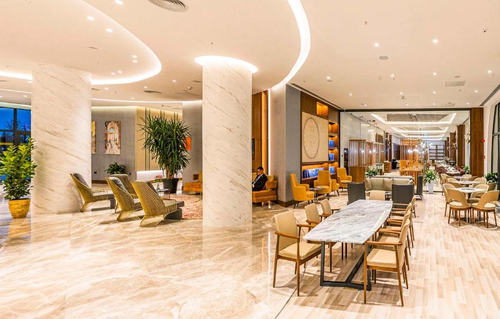 a restaurant with tables and chairs in a lobby at Hilton Garden Inn Samarkand Afrosiyob in Samarkand