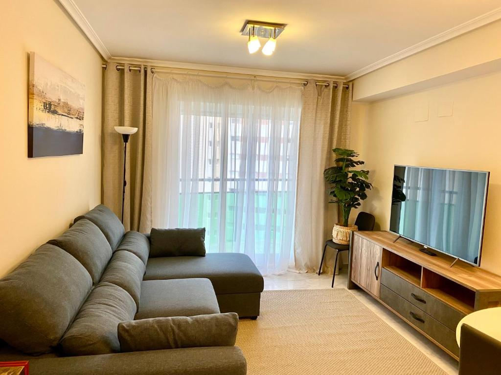 ein Wohnzimmer mit einem Sofa und einem Flachbild-TV in der Unterkunft Apartamento Mar y Sol Benidorm in Cala de Finestrat