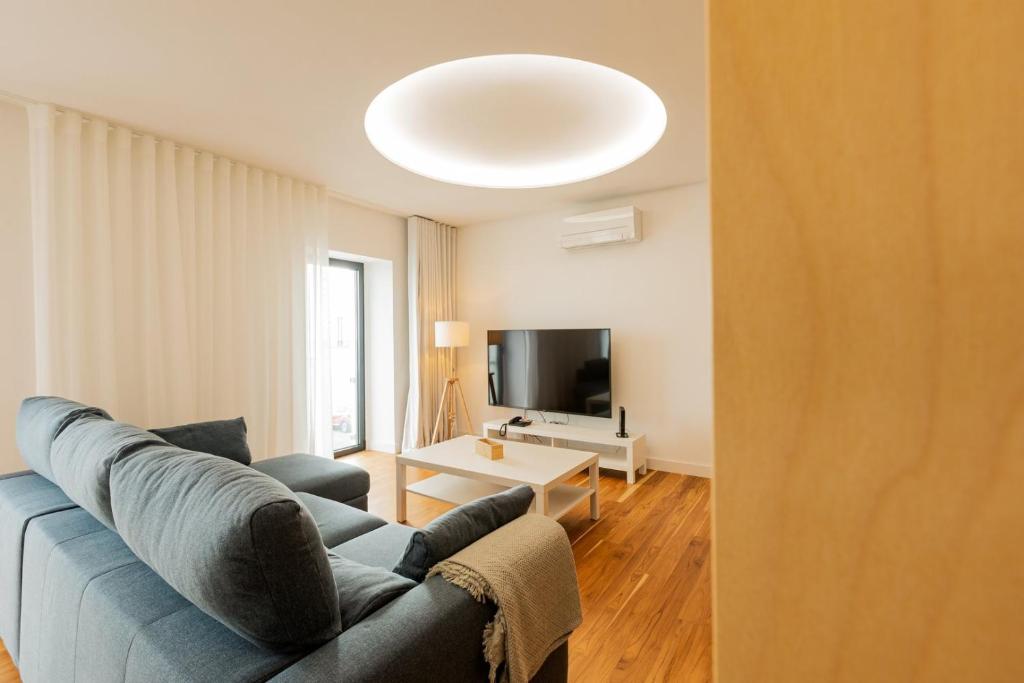 a living room with a blue couch and a tv at Casa Rua da Fonte - Modern & Relax (Bay View) in Ponta Delgada