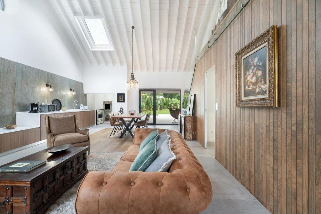 a living room with a brown couch and a kitchen at WelcomeBuddy - São Brás Collection Jacuzzi&Garden in Porto Formoso