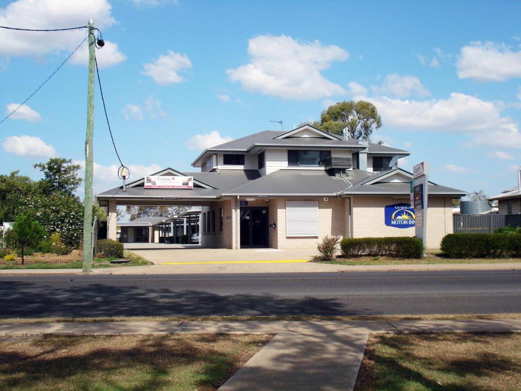 a white house with a blue roof and some trees at Oakey Motor Inn in Oakey