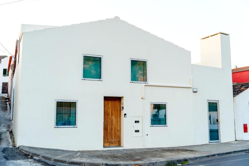 un edificio bianco con una porta in legno su una strada di WelcomeBuddy - Villa Wave N'Sea - Beachfront a Mosteiros