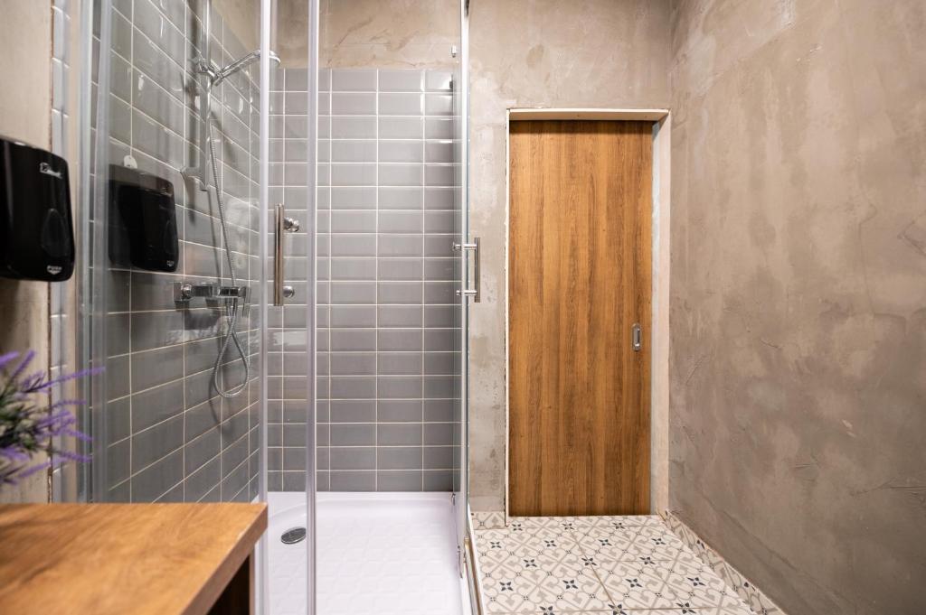 La salle de bains est pourvue d'une douche et d'une porte en bois. dans l'établissement Central Square Apartments, à Belgrade
