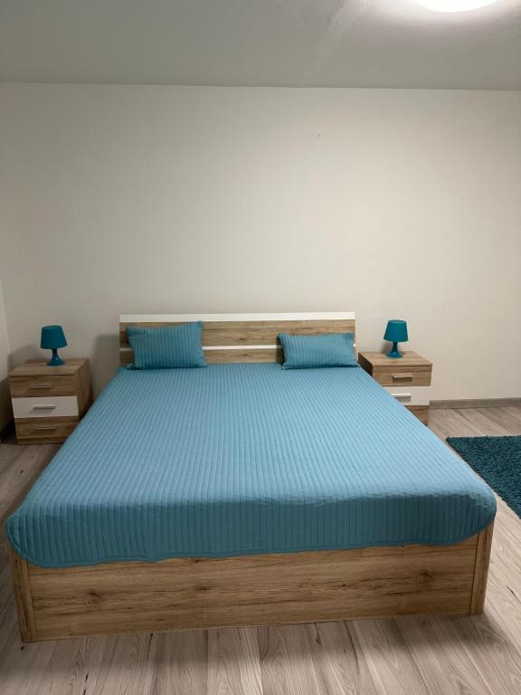 Útulný byt Brezno v Nízkych Tatrách في برزنو: غرفة نوم مع سرير ذو أغطية زرقاء ومخدات زرقاء