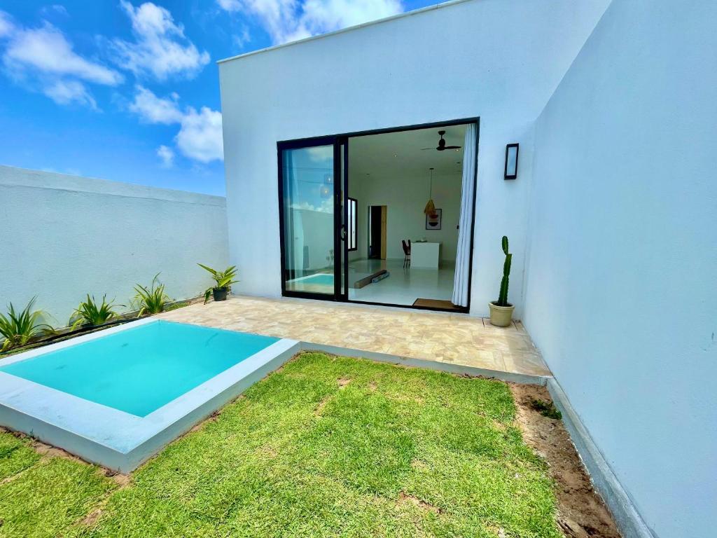 a white house with a swimming pool in the yard at Casa privativa na Vila Ser tão zen #02 in Tibau do Sul