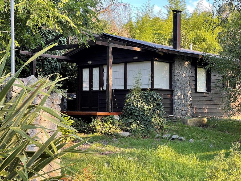 una casa de piedra con porche en un patio en Cabaña Bosque Peralta Ramos en Mar del Plata
