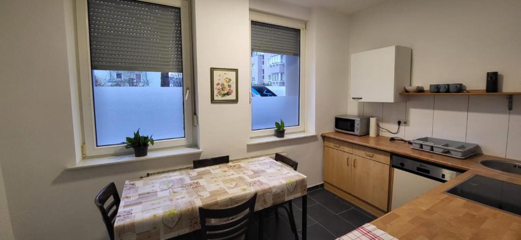 eine Küche mit einem Tisch und 2 Fenstern sowie einem Tisch und Stühlen in der Unterkunft Apartment bei Michael Bochum in Bochum