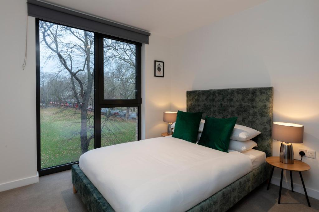 sypialnia z dużym łóżkiem i dużym oknem w obiekcie Deluxe North Central London Apartment w Londynie