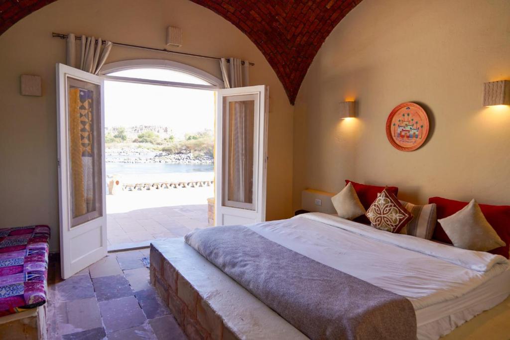Artika Wadi Kiki Hotel في أسوان: غرفة نوم بسرير كبير وباب مفتوح
