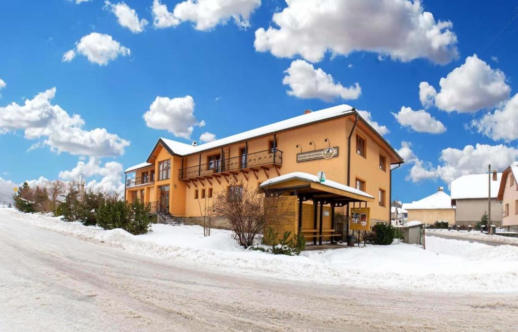 a building on the side of a snow covered road at Penzión pod Kýčerou in Zuberec