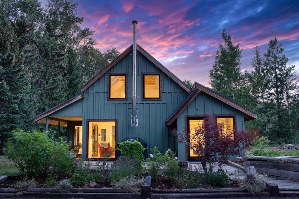 a green house with a sunset in the background at Charming Scandinavian Modern Riverfront Fishhouse in Hailey