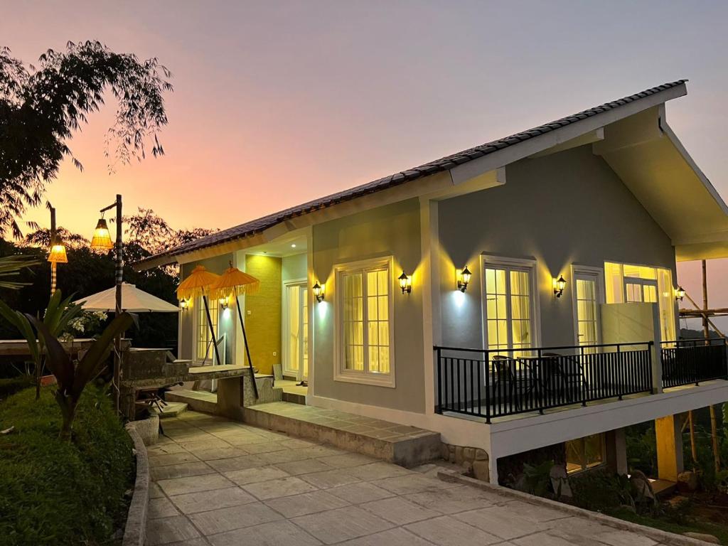 een klein geel huis met een zonsondergang op de achtergrond bij One Ubud Village in Gunungpicung