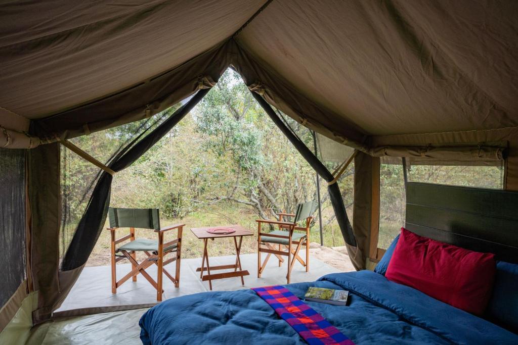 a bedroom in a tent with a table and chairs at Olimba Mara Camp in Mara Simba