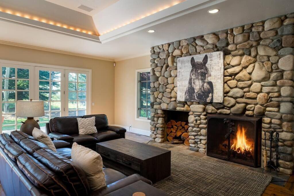 a living room with a stone wall with a fireplace at Gimlet Family Home Close to Lift with Hot Tub! in Hailey