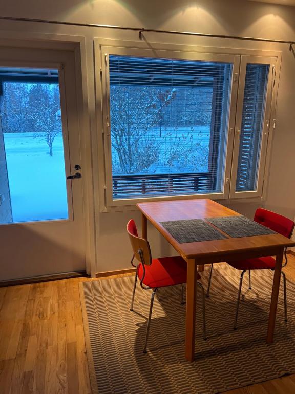 a table and chairs in a room with two windows at AaltoStudio Alajärvi-Center in Alajärvi