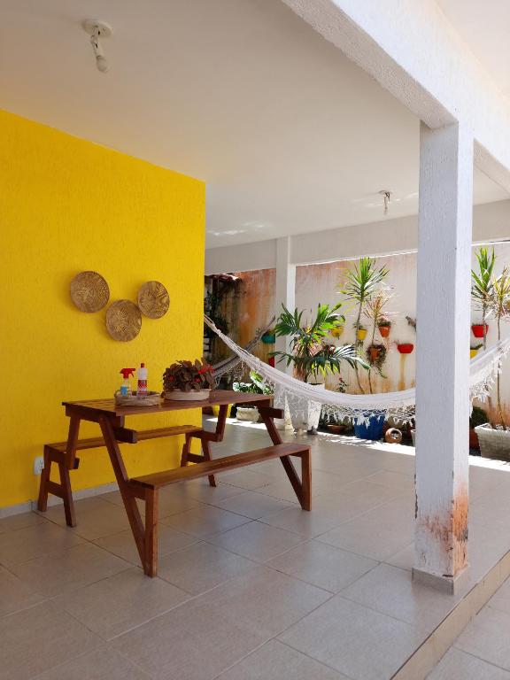 uma sala de estar com uma mesa e uma parede amarela em Casa Meu Cantinho em Barra de São Miguel