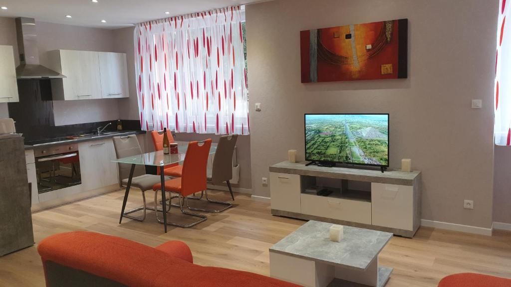 - un salon avec une télévision et une table avec des chaises dans l'établissement Meublés du 25 N2 F2 RDC, à Niederbronn-les-Bains