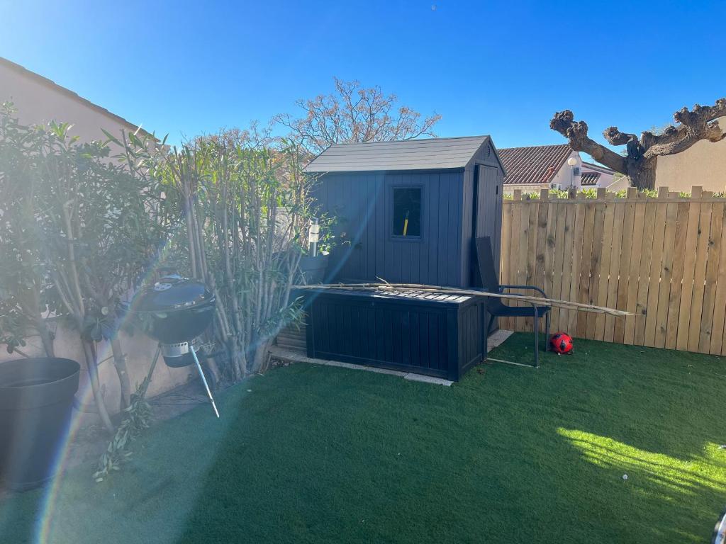 une cour avec un abri bleu sur l'herbe dans l'établissement Maison saint cyprien plage, à Saint-Cyprien
