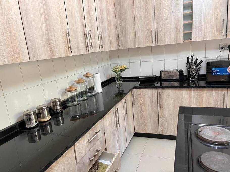 a kitchen with wooden cabinets and a black counter top at Four m luxury Apartment. in Kitwe