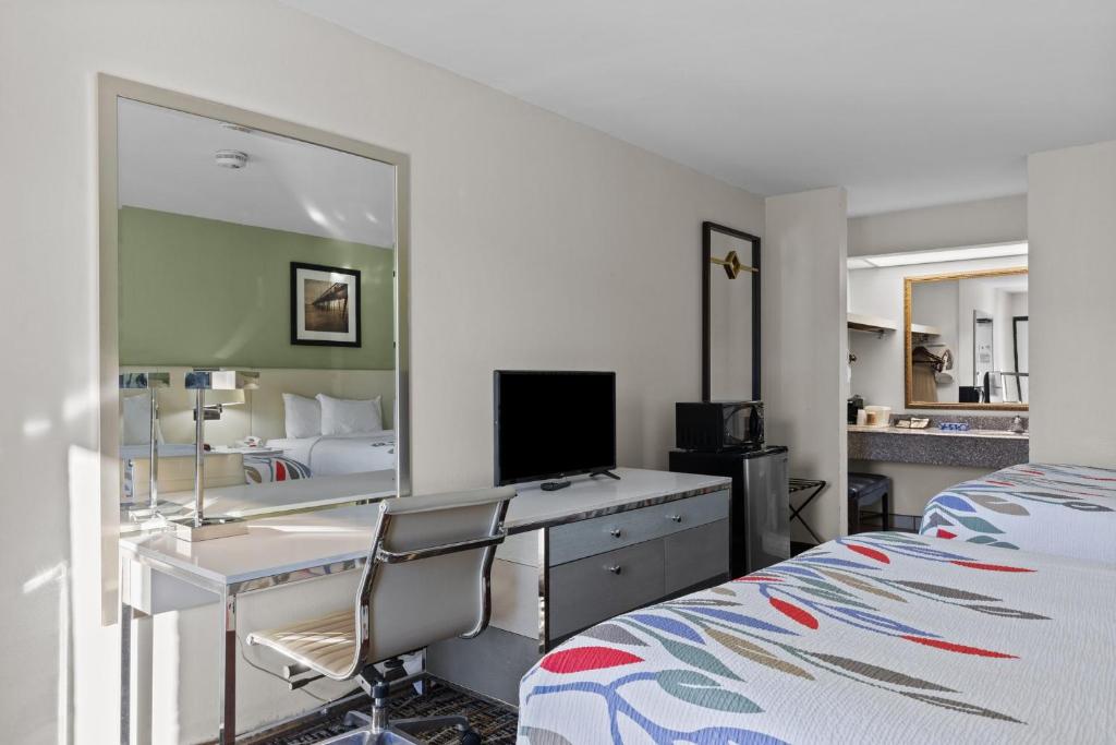 莫爾黑德城的住宿－Garnet Inn & Suites, Morehead City near Atlantic Beach，一间卧室配有书桌、一张床和镜子