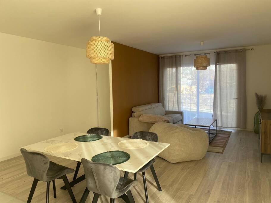 - un salon avec une table, des chaises et un canapé dans l'établissement Maison By Sana proche du lac, à Châtellerault