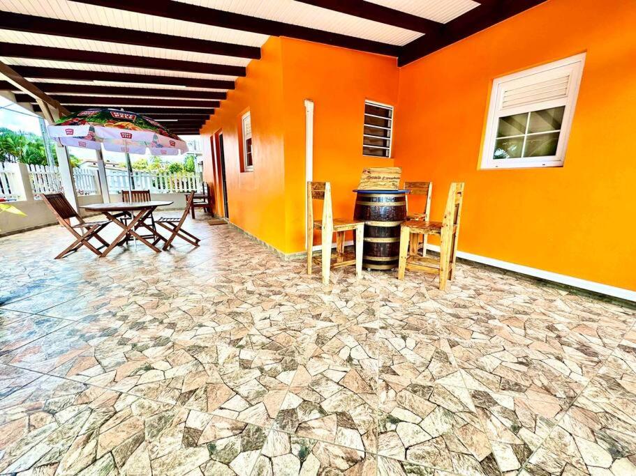 Cette chambre est dotée d'un mur orange avec une table et des chaises. dans l'établissement Villa Dom's Evasion, à Sainte-Marie