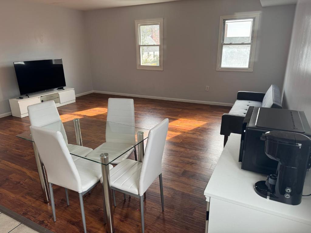 a living room with a glass table and white chairs at Cozy apartment nexttomain st in Passaic