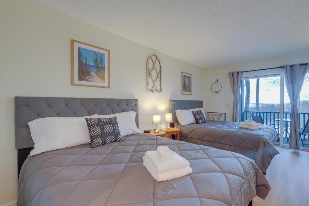 1 dormitorio con 2 camas y balcón en Bellaire Condo - Walk to Shanty Creek Resort!, en Bellaire