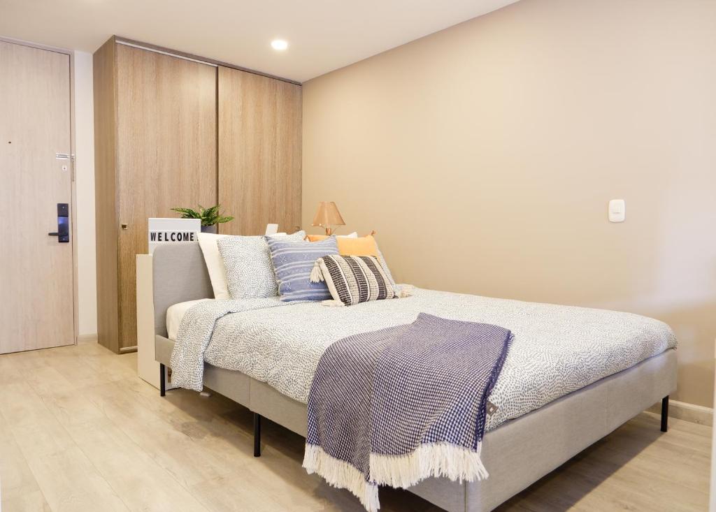 - une chambre avec un lit doté d'oreillers bleus et blancs dans l'établissement The Petit Flat - Bright & stylish studio apartment near Unicentro, à Bogotá