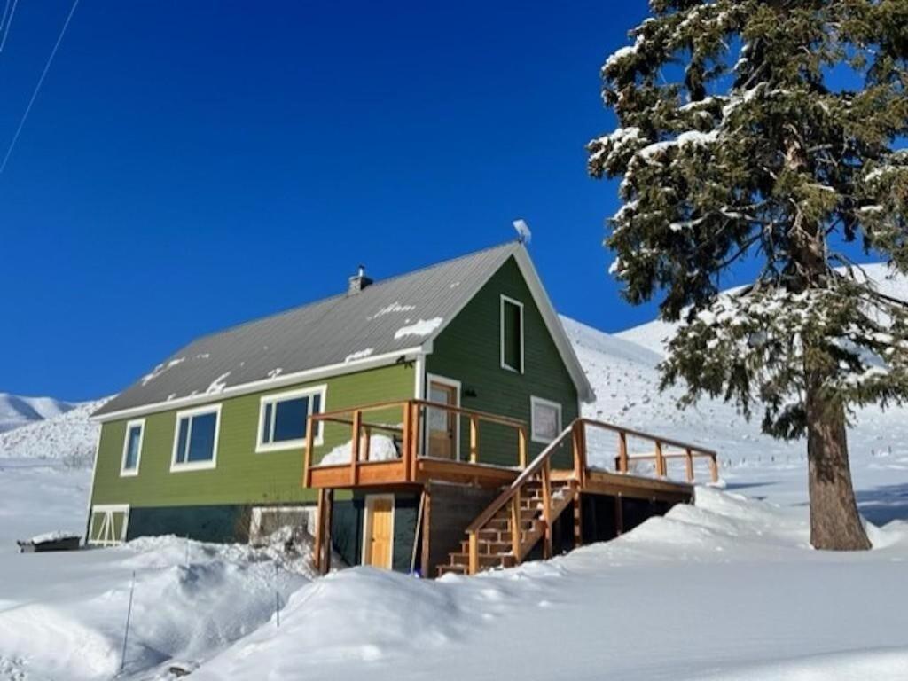 una casa verde con un ponte nella neve di Triumph Ranch Farm House ad Hailey