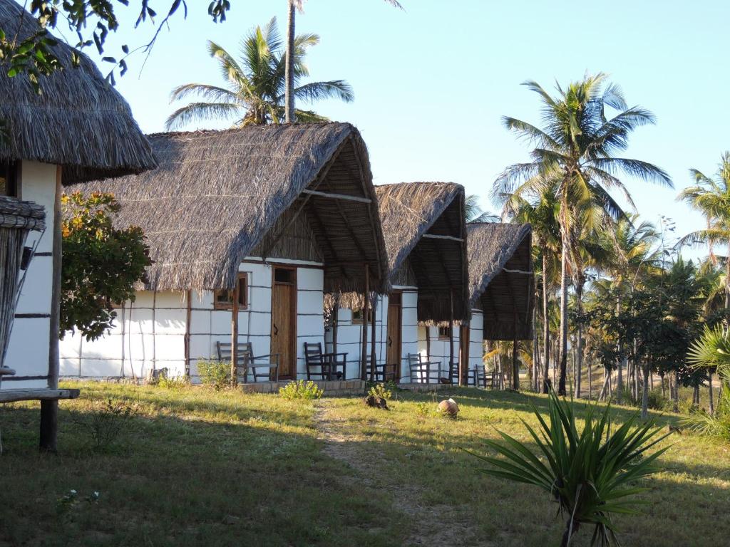 una fila de casas con techos de paja y palmeras en DUNA LODGE en Gudze