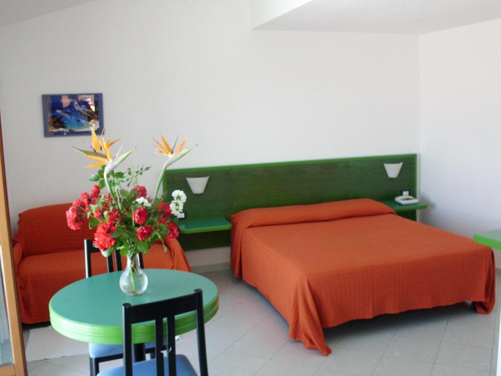 a bedroom with a bed and a table with a vase of flowers at Hotel Piccada in Palau