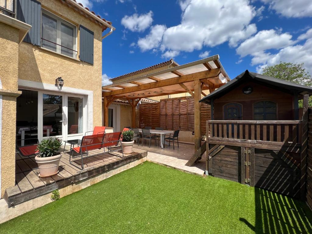 une cour avec pergola en bois et pelouse dans l'établissement Villa complète, à Nîmes