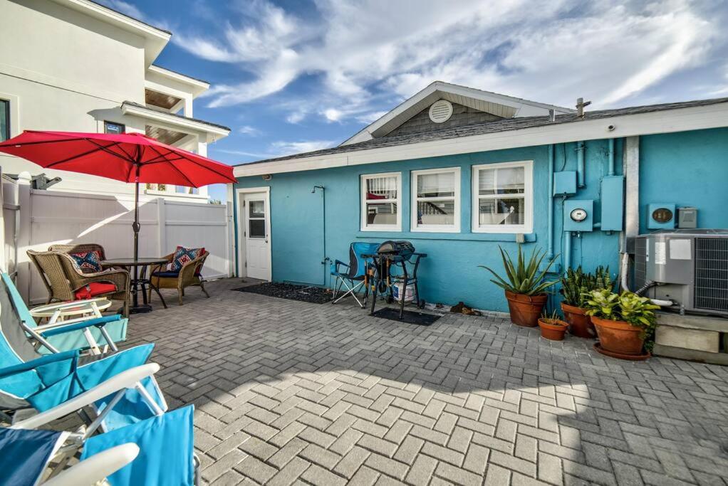 a blue house with a patio with a table and an umbrella at Beautiful Waterfront Beach Cottage. Sleeps 6 in Clearwater Beach