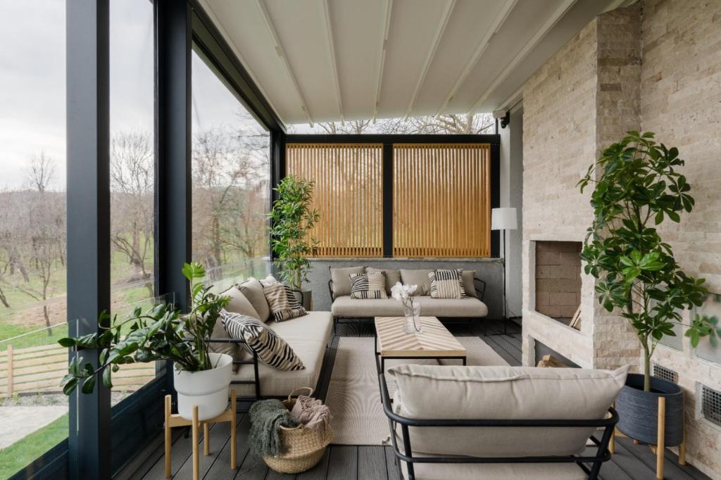 a screened porch with a couch and chairs and plants at Villa The Frame in Comarnic