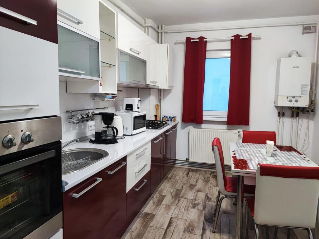 une cuisine avec une table et un rideau rouge dans l'établissement Apartament Racadau, à Braşov