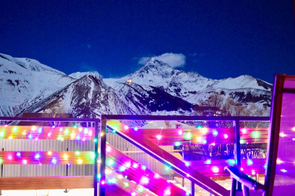 a building with lights in front of a snow covered mountain at SMART Via Kazbegi in Stepantsminda