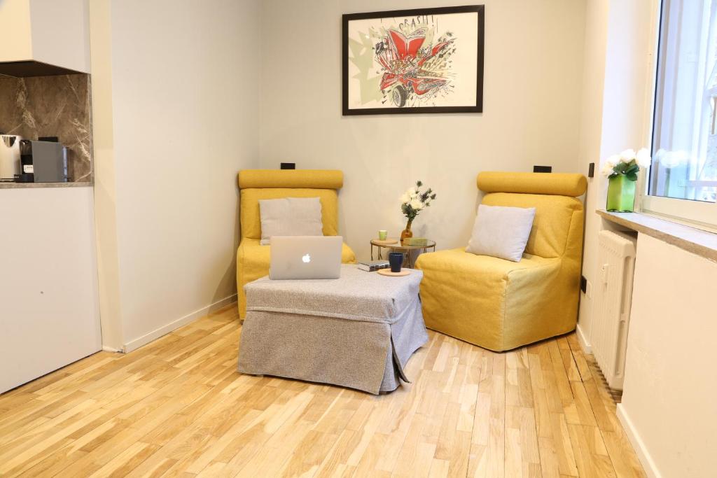 een woonkamer met 2 gele stoelen en een laptop bij Meyland suites centro in Milaan
