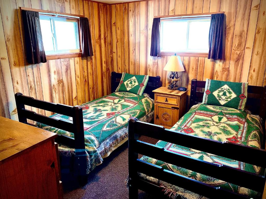 1 Schlafzimmer mit 2 Betten, einem Tisch und 2 Fenstern in der Unterkunft Benzonia Rustic Resort in Benzonia