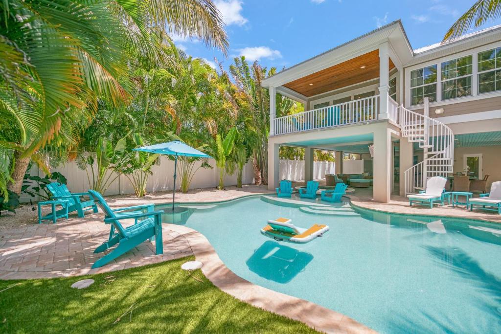 a swimming pool with chairs and a house at Southern Exposure AMV in Anna Maria
