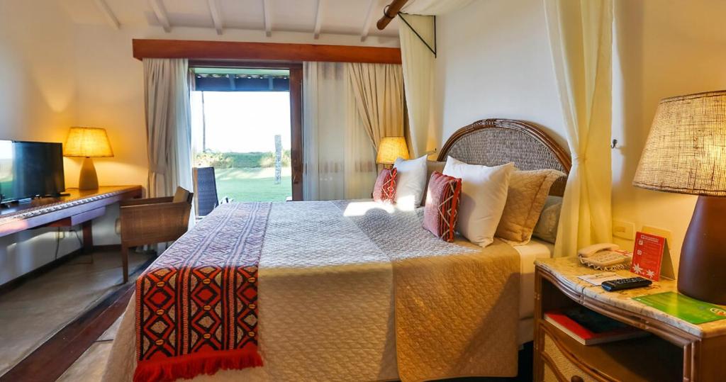 Transamerica Comandatuba - All Inclusive Resort في إلها دي كومانداتوبا: غرفة نوم بسرير مع مكتب وتلفزيون